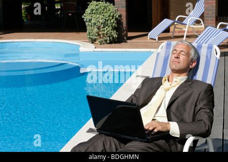 Geschäftsmann mit Laptop-Computer ruht auf Liegestuhl Stockfoto