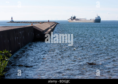 Die Mole und Leuchtturm an der Marquette, Michigan mit einem vorbeifahrenden Frachter. Stockfoto