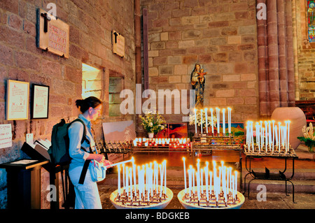 Frankreich, Jakobsweg: Frau brennende Kerze in der Pfarrkirche Eglise Notre Dame Stockfoto