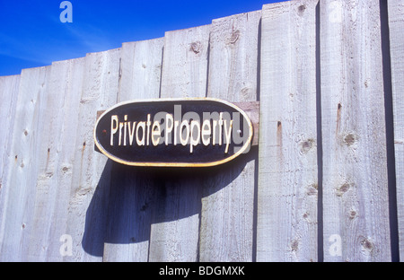 Oval gegossen Blechschild am Holzzaun unter blauem Himmel wirft Schatten und Angabe von Privateigentum Stockfoto