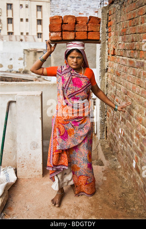 Frauen, die die Ziegel auf den Kopf. Sie arbeitet auf einer Baustelle in einer Stadt in Indien. Diese Frauen sind gering bezahlten Arbeitnehmer. Stockfoto