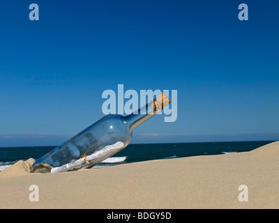 Eine Flasche mit einer Nachricht im Inneren wird am Strand begraben. Stockfoto