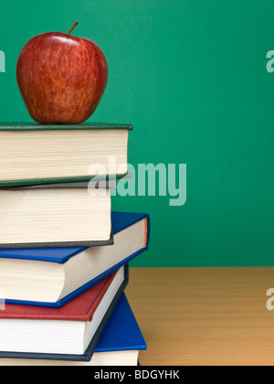 Eine leere Tafel mit einem Apfel auf einem Stapel Bücher. Stockfoto