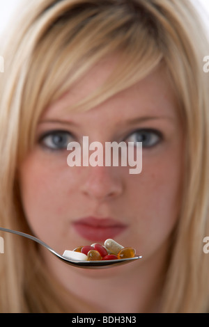 junge 20 jährige blonde Frau mit einem Löffel Vitamin Ergänzungen Stockfoto
