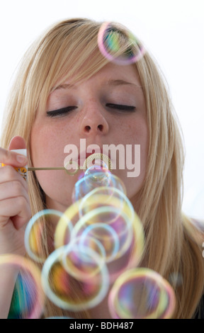 junge 20 jährige blonde Frau bläst Seifenblasen aus einem Kinder-Spielzeug Stockfoto