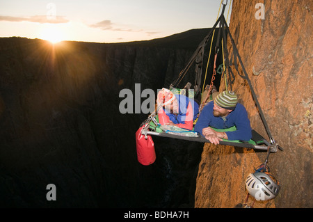 Ein Mann und eine Frau auf einem Portaledge bei Sonnenuntergang beim Klettern eine vertikale Fläche in Gunnison, Colorado. Stockfoto