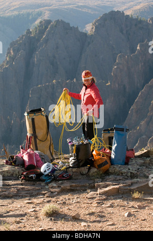 Eine Frau, wickeln ein Kletterseil neben mehreren Taschen der Ausrüstung in den Bergen von Crawford, Colorado. Stockfoto