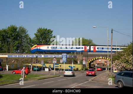 Personenzug Überfahren einer Eisenbahnbrücke mit Verkehr Reisen darunter in Market Harborough, Leicestershire Stockfoto