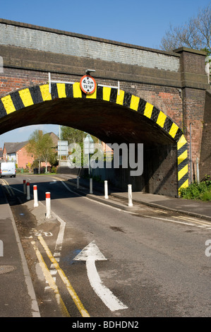 Straßenmarkierungen Führung Verkehr Gänsemarsch unterhalb einer Höhe eingeschränkt Eisenbahnbrücke in England Stockfoto