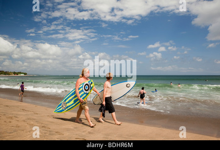 Indonesien, Bali, Kuta, Strand, Vater und Sohn Surfer Gewässer entlang Rand mit Surfbrettern Stockfoto