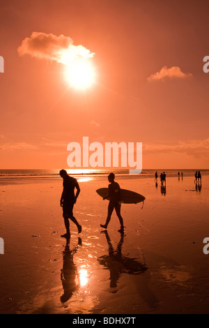 Indonesien, Bali, Kuta, Strand, Surfer bei Sonnenuntergang entlang nassen Sand am Ende der Tage Surfen Stockfoto