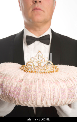 Butler hält eine Tiara auf einem Kissen Stockfoto