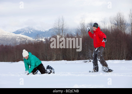 Paar tragen Schneeschuhe haben eine Schneeballschlacht, Whistler, Britisch-Kolumbien, Kanada Stockfoto