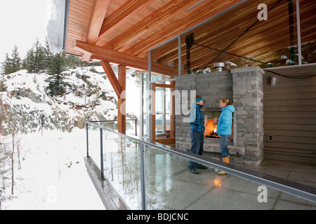 Paar steht auf Balkon des Chalet im Winter, Whistler, Britisch-Kolumbien, Kanada Stockfoto