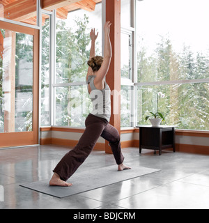 Frau beim Yoga im Wohnzimmer großen alpinen Hauses Stockfoto