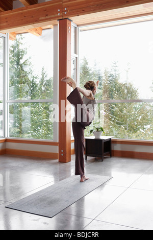 Frau beim Yoga im Wohnzimmer großen alpinen Hauses Stockfoto