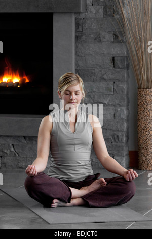 Frau zu Hause vor dem Kamin zu meditieren Stockfoto