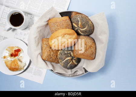 Sortiment von Brot Brötchen mit Zeitung, Kaffee und Croissant Hälfte gegessen Stockfoto