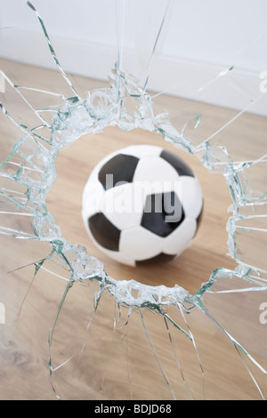 Fußball und zerbrochenes Fenster Stockfoto