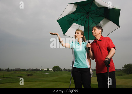 Vater und Tochter auf dem Golfplatz mit einem großen Sonnenschirm Stockfoto