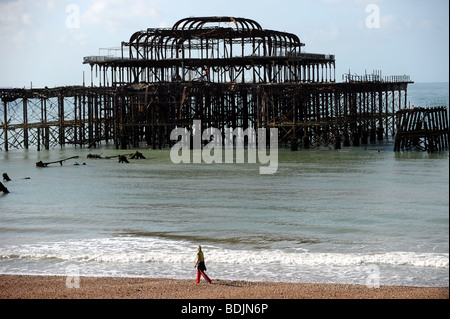 Einsame Frau von West Pier Brighton bei Ebbe zu Fuß in den frühen Morgenstunden UK Stockfoto