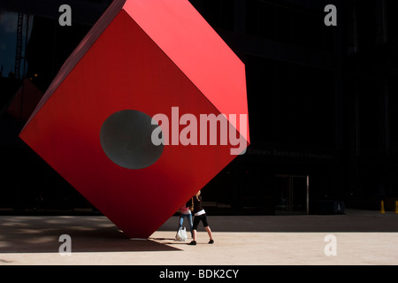 Leute behaupten, groß angelegte Kunst im öffentlichen Raum Skulptur Red Cube (1968) von Künstler Isamu Noguchi zu unterstützen. Stockfoto