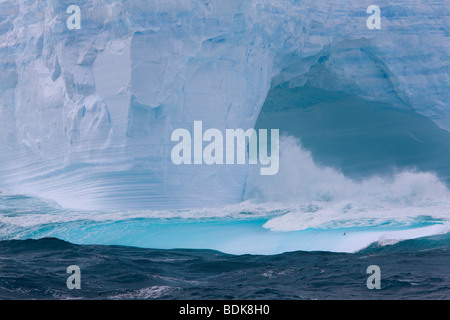 Wave waschen über den Ausgangspunkt der großen blauen Eisberg durch grobe Ocean Wave action schöne türkisblaue Farbe kleiner Vogel in Spray flying ausgehöhlten Stockfoto