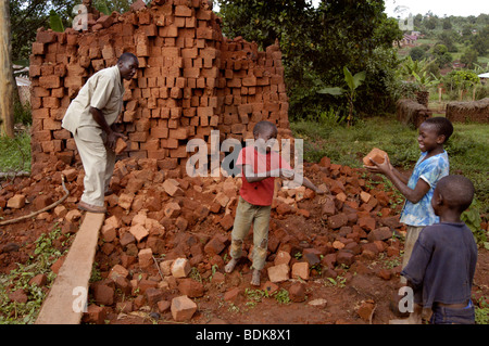 Ein Mann und drei Kinder arbeiten zusammen, um stapeln und unstack Ziegel für den Bau eines Hauses in Ost-Afrika Afrika uganda Stockfoto