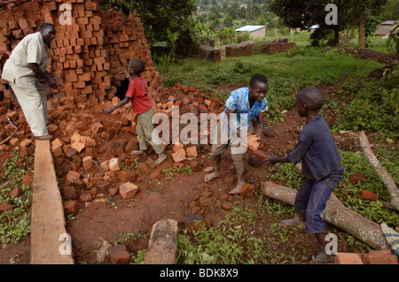 Ein Mann und drei Kinder arbeiten zusammen, um stapeln und unstack Ziegel für den Bau eines Hauses in Uganda Ostafrika african Stockfoto