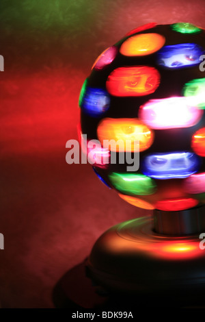 rotierende Spielball mit bunten Lichtern auf Tisch im dunklen Raum Stockfoto