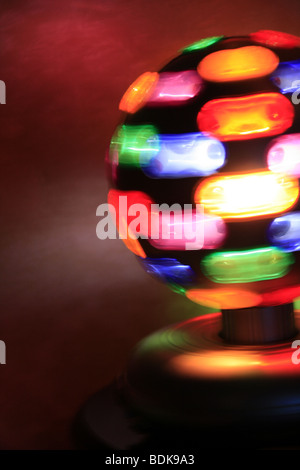 rotierende Spielball mit bunten Lichtern auf Tisch im dunklen Raum Stockfoto