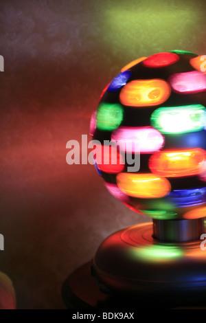 rotierende Spielball mit bunten Lichtern auf Tisch im dunklen Raum Stockfoto