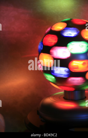 rotierende Spielball mit bunten Lichtern auf Tisch im dunklen Raum Stockfoto