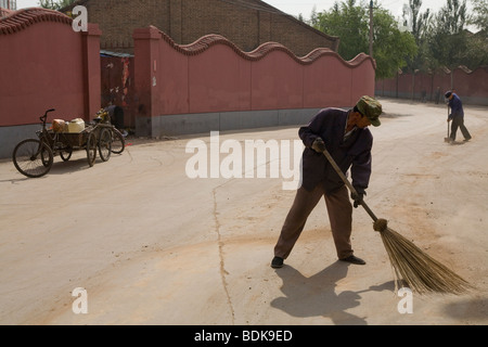 DATONG, Provinz SHANXI, CHINA - AUGUST 2007: Kehrmaschinen reinigen die Straße mit breiten Besen in einem alten Teil der Stadt. Stockfoto