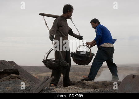 WUDA COAL FIELD, WU HAI, Innere Mongolei, CHINA - AUGUST 2007: Liang Yan Fa trägt Körbe gesiebte Kohle, Schwefel zu machen. Stockfoto