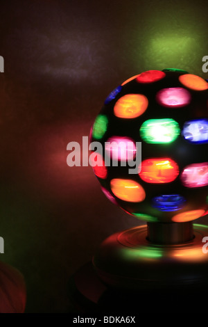 rotierende Spielball mit bunten Lichtern auf Tisch im dunklen Raum Stockfoto