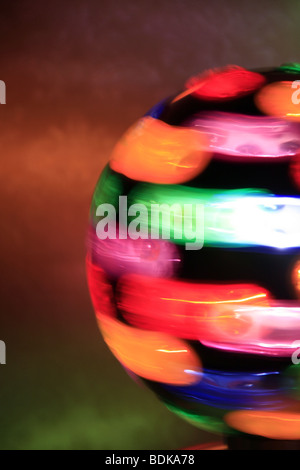 rotierende Spielball mit bunten Lichtern auf Tisch im dunklen Raum Stockfoto