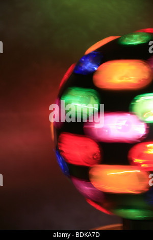 rotierende Spielball mit bunten Lichtern auf Tisch im dunklen Raum Stockfoto