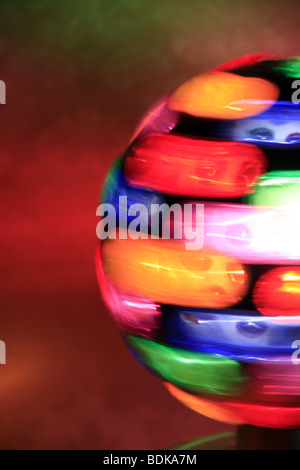 rotierende Spielball mit bunten Lichtern auf Tisch im dunklen Raum Stockfoto