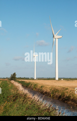 ein Fenland Windpark vor blauem Himmel mit einer Entwässerungsrinne im Vordergrund Stockfoto