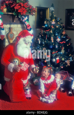 Jolly altes St. Nick junge Mädchen Baby präsentiert Weihnachtsbaum Morgen Kamin Stockfoto