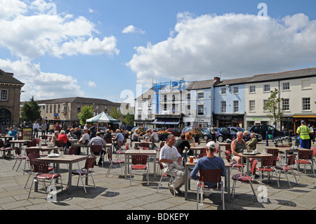 Leute sitzen draußen bei Lloyds-Café-Tischen genießen al fresco Sommersonnenschein Market Square Warwick England Stockfoto