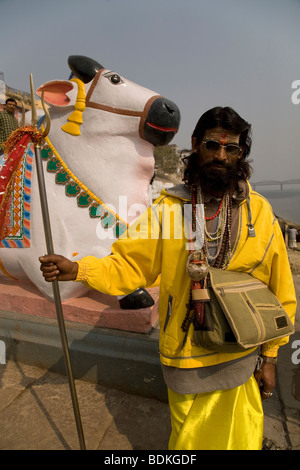 Ein Sadhu in der indischen Stadt Varanasi (Benares). Er steht vor einer Statue von Nandi, Shivas Fahrzeug. Stockfoto