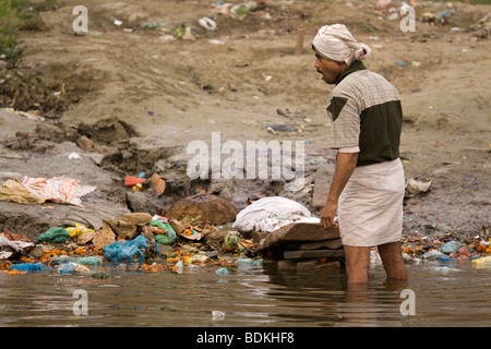 Ein Dhobi (Wäsche Mann) wäscht Kleidung an den Ufern des Flusses Ganga (Ganges) in Varanasi, Indien. Stockfoto