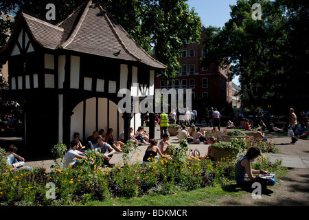 Menschen versammeln, um entspannen in der Sonne um die Mittagszeit in Soho Square (auch bekannt als Soho Beach) im Zentrum von London. Stockfoto
