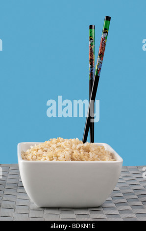 Brauner Reis in weiße Schale mit Stäbchen Stockfoto