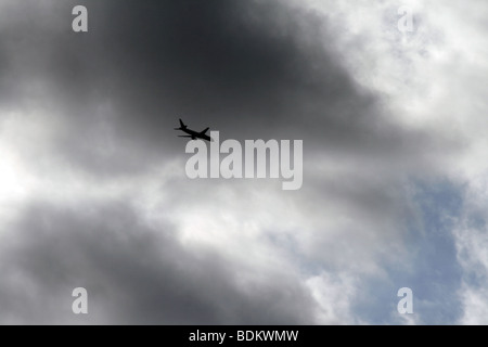 Flugzeug fliegen durch dunkle Wolken im Himmel Stockfoto