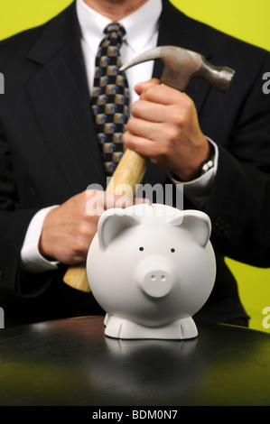 Geschäftsmann hält eine Hemmer vor Piggy bank Stockfoto