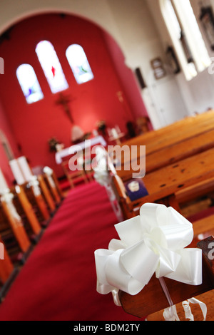 Closeup weißes Band Bogen Tag Hochzeitsdekoration Kirche Bestuhlung in kleinen bunten Kirche UK Stockfoto