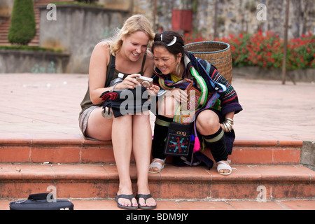 Kaukasische Touristen zeigt einer traditionell gekleideten Hmong-Mädchen einige Fotos von einer Kamera Stockfoto